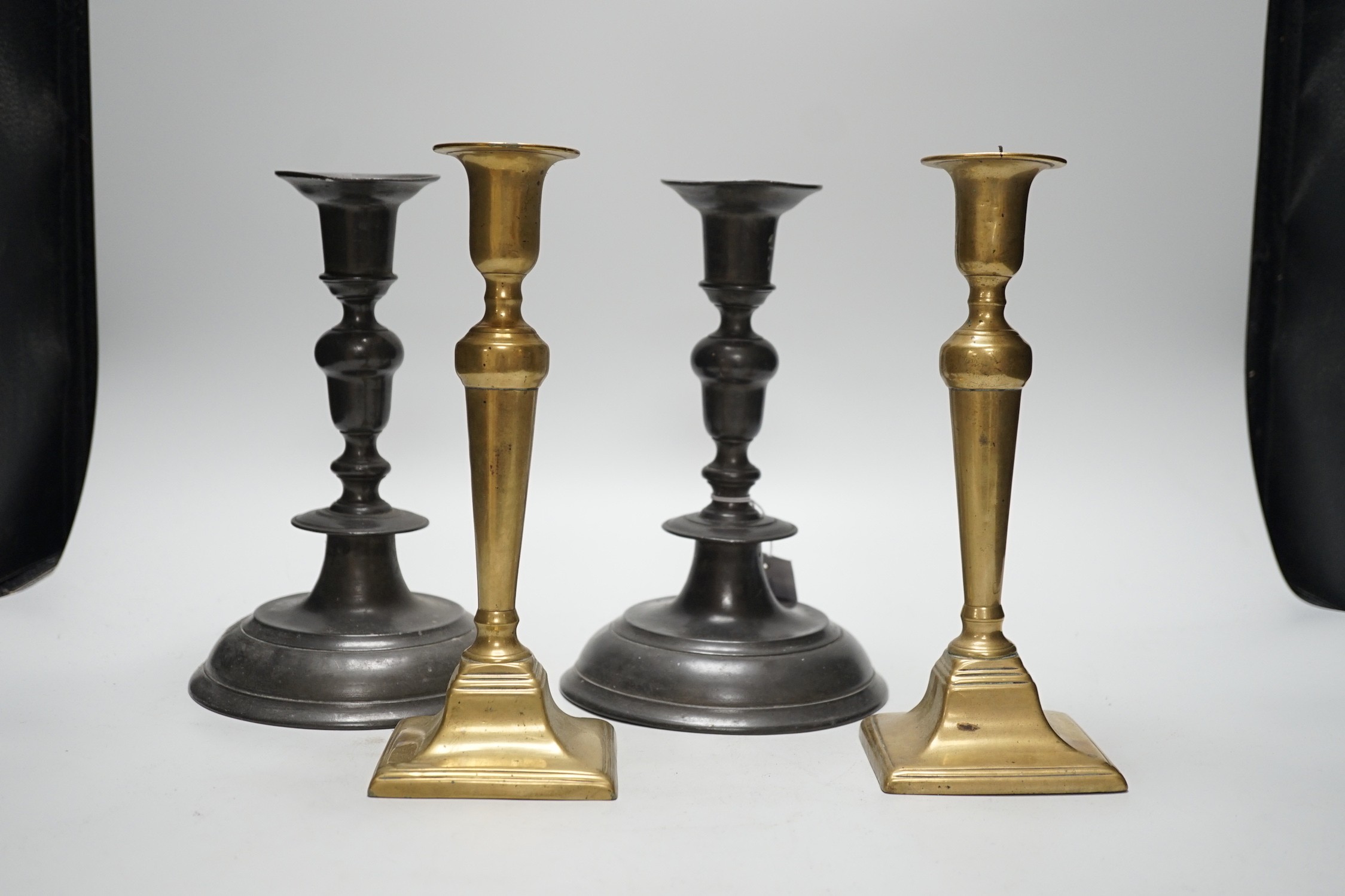 A pair of 18th century continental, possibly German, pewter candlesticks- 24cms high and a pair of late Georgian brass candlesticks